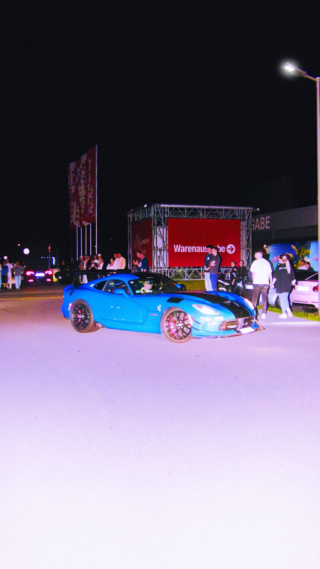 Blaues Fahrzeug auf einem nächtlichen Automotive Event.